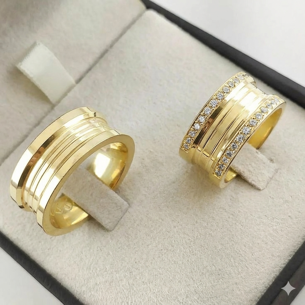 Par do Modelo Carretel, com frisos na parte central, 9mm largura. No modelo 1 cravação de pedras nas bordas em toda circunferência da aliança, média de 80 pedras. Ouro Amarelo - Tradicional 18k/750