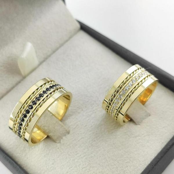 Par do Modelo reto, com fio trançado em baixo relevo nas laterais, parte central com pedras (80 em média no par), cravejadas em toda circunferência da aliança, 10mm largura em Ouro Amarelo - Tradicional 18k/750